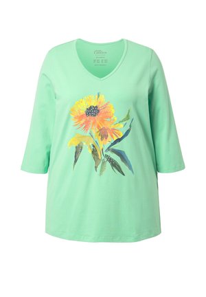 Chemise vert menthe à encolure en V avec manches trois-quarts, ornée d'un grand motif floral jaune et orange de style aquarelle avec des feuilles vertes.