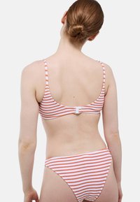 Ensemble bikini rayé avec des rayures horizontales orange et blanches, doté de bretelles réglables et d'un fermoir à l'arrière. Tissu doux et texturé.