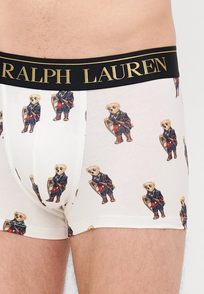 Biele boxerky so vzorom kreslených medveďov v čiernych oblekoch. Čierny elastický pás s nápisom "RALPH LAUREN" zlatým písmom.