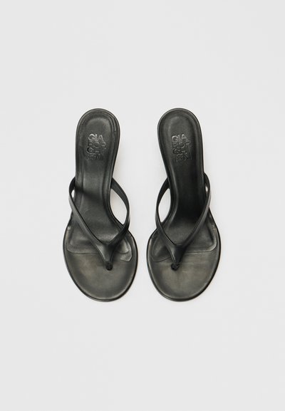 Čierne šľapky vyrobené z hladkej gumy, s minimalistickým dizajnom a tenkými popruhmi, majú tvarovanú stielku.