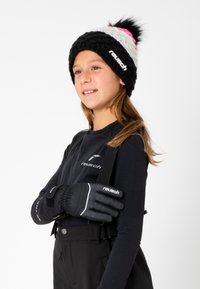 Gebreide beanie met zwarte, roze en witte strepen en pompon; zwarte handschoen met gestructureerde grip; zwart langemouwen top en bretelbroek.