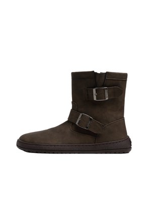 Bota marrón hasta la mitad de la pantorrilla con dos hebillas metálicas ajustables y una suela plana con ranuras sobre un fondo blanco.