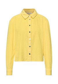 Chemise à manches longues en velours côtelé jaune avec col pointu et boutons-pression sur le devant, présentant une coupe légèrement raccourcie et carrée.