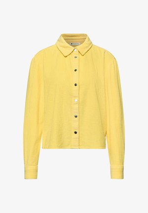Chemise à manches longues en velours côtelé jaune avec col pointu et boutons-pression sur le devant, présentant une coupe légèrement raccourcie et carrée.