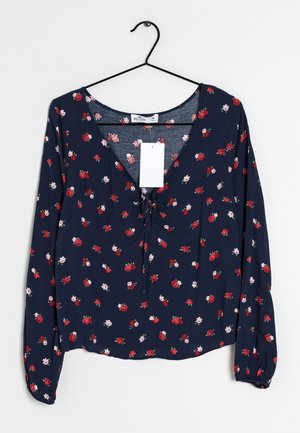 Marineblauwe bloemenblouse met lange mouwen, voorzien van kleine rode en roze bloemen, een V-hals en een trekkoorddetail aan de voorkant.