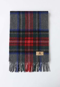 Écharpe en laine grise avec un motif tartan aux lignes rouges, vertes et bleues. Fini avec des bords frangés et un patch en cuir.