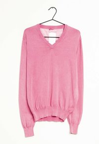 Vaaleanpunainen V-pääntie neulepaita, joka on valmistettu pehmeästä kankaasta. Siinä on pitkät hihat, joissa on kerättyjen hihansuiden yksityiskohta, sekä istuva vyötärö. Tagi näkyy kaula-aukossa.