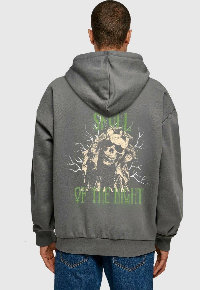 Felpa grigia con cappuccio caratterizzata da una grande grafica di teschio e testo verde che recita "SMULL OF THE NIGHT" con design simili ad alberi. Tessuto morbido e vestibilità rilassata.
