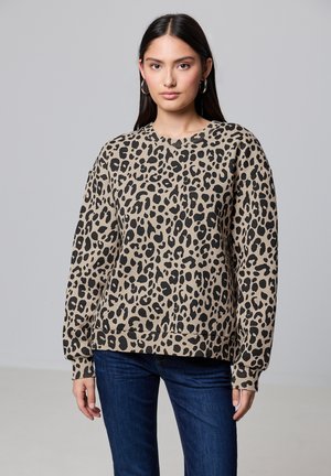 Leopardenmuster-Sweatshirt, beiger Grundton mit schwarzen Flecken, runder Ausschnitt, lange Ärmel, gerippte Bündchen und Saum, kombiniert mit dunkelblauen Jeans.