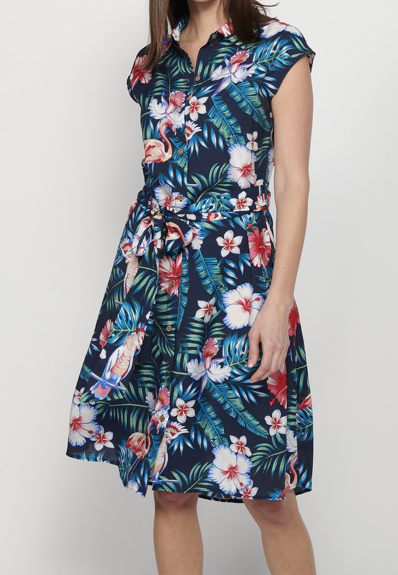 Kurzärmliges, knöpfiges Kleid aus marinefarbener Stoff mit floralem Muster, das rote und weiße Blumen sowie grüne Blätter zeigt und in der Taille gebunden ist.