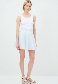 Canotta bianca con embellishments argentati, abbinata a una gonna svasata a righe blu e bianche. Tessuti lisci, design casual, lunghezza sopra il ginocchio.