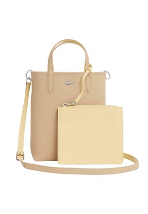 Beige rektangulær shopper med top-håndtag og aftagelig skulderrem, kombineret med en mindre lysegul håndledspung fastgjort foran.