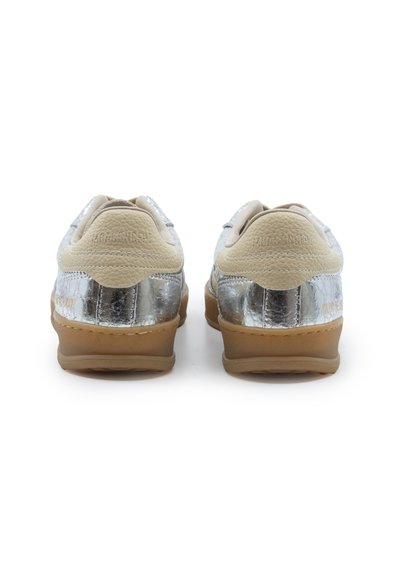 Coppia di sneakers basse con rinforzi del tallone in pelle beige, lati con trama metallica argentata e suole in gomma marrone, viste da dietro.