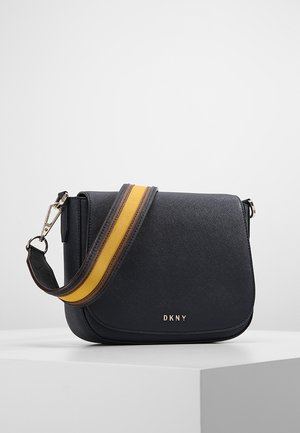 Černá crossbody taška DKNY s klopou a širokým nastavitelným popruhem se žlutými a hnědými pruhy, kovovými úchyty a přezkami.
