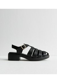 Sandalo in pelle nera con tacco a blocco, caratterizzato da larghe cinghie e una fibbia regolabile alla caviglia. Texture liscia e design con punta aperta.
