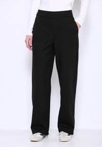 Zwarte wijde broek met een gladde textuur en elastische tailleband, voorzien van zijzakken en een gepaste pasvorm voor comfort.