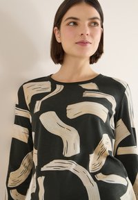 Košile s dlouhým rukávem v tmavě zelené barvě s béžovým abstraktním vzorem štětcových tahů. Kulatý výstřih a volný střih. Jemná textura.