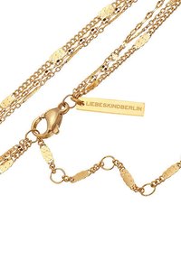 Guldfärgad kedjehalsband med flera strängar, med platta ovala länkar, en kräfta clasp och en rektangulär taggs som är graverad med "LIEBESKINDBERLIN."