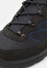 Schwarzer Wanderschuh mit strukturiertem Mesh-Obermaterial, Wildlederakzenten, blauen Nähten und metallischen Ösen mit Schnürsenkeln für einen sicheren Sitz.