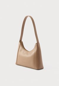 Mala de ombro em couro castanho claro com forma curva, textura suave e fecho de correr dourado. Apresenta uma única alça alongada. Design minimalista.