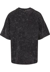 Sort vasket bomulds t-shirt med en afslappet pasform, brede ærmer og en struktureret overflade. Ingen synlige logoer eller mønstre. Vist fra bagsiden.