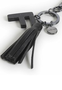 Portachiavi nero con una forma geometrica opaca nera, una frangia in pelle e un'etichetta circolare in tono argento incisa con "MIRIADA."