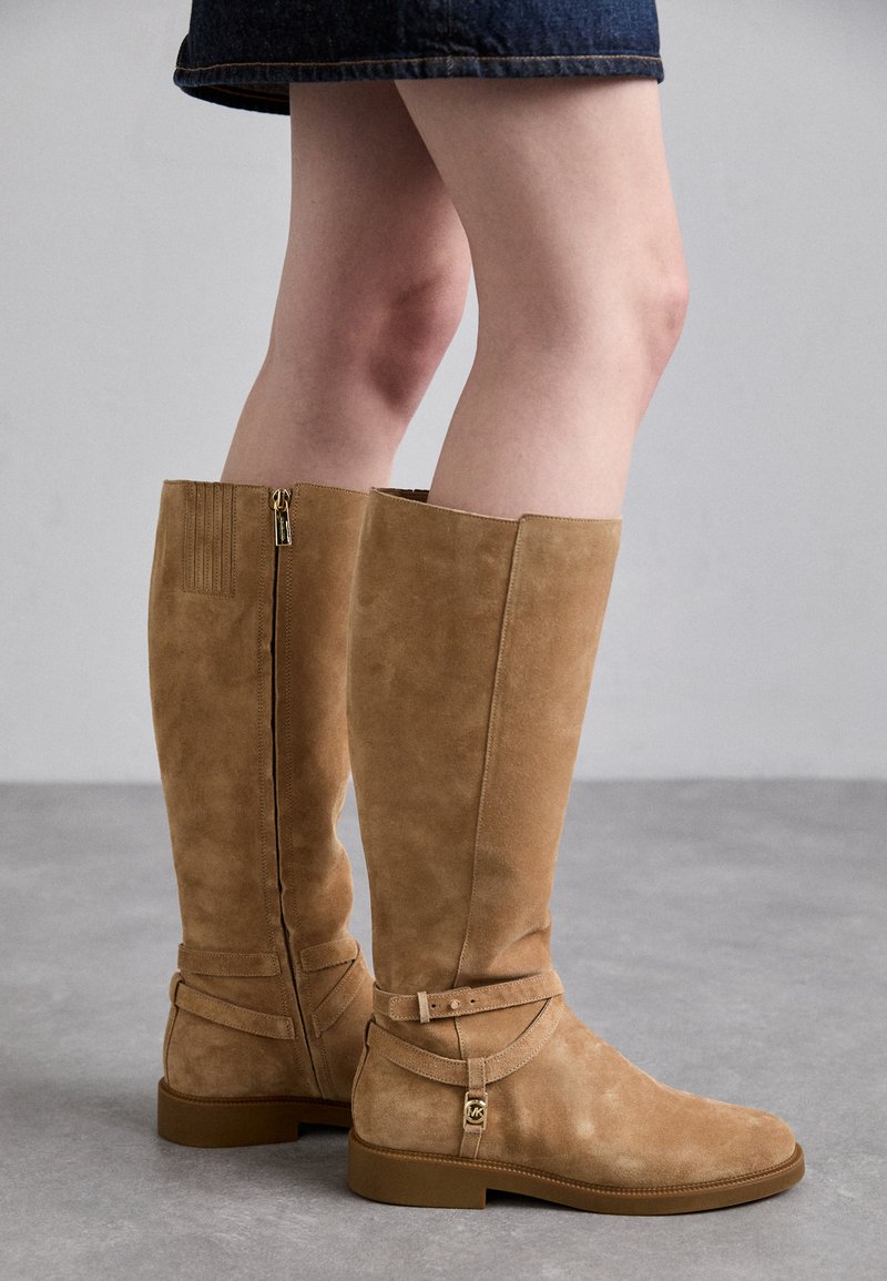 Knee-high brązowe zamszowe botki z zamkiem z tyłu, z akcentującymi paskami wokół kostki oraz teksturowaną cholewką dla dodatkowego szczegółu.