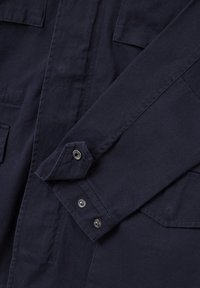 Dunkelblauses Hemd mit zwei Brusttaschen, Knopfmanschetten und einer glatten Textur. Hergestellt aus einem strapazierfähigen Stoff mit sauberen Nähdetails.