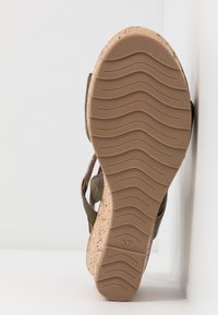 Sandale à semelle en liège avec semelle en caoutchouc antidérapante, présentant des lanières olive et un design texturé. Taille 37 imprimée au fond.