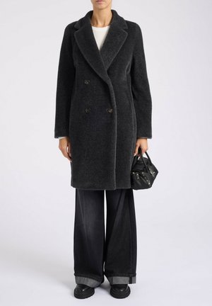 Cappotto grigio doppiopetto con revers ampi, tessuto strutturato, due bottoni frontali, abbinato a jeans scuri a gamba larga e una piccola borsa nera.