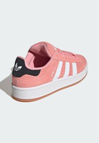 Rosa Wildledersneaker mit weißen Streifen und schwarzem Fersenakzent. Verfügt über einen gepolsterten Kragen und eine strukturierte Gummisohle für besseren Halt.