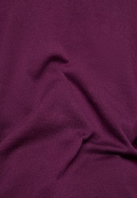 Strukturiertes Gewebe in tiefem Lila, mit einer gerippten Oberfläche und subtilen Falten, das dieflexible und weiche Materialqualität zur Schau stellt.