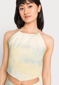 Top cropped com decote halter em cores pastel claras com um padrão de tie-dye; apresenta um decote franzido e um ajuste cropped e descontraído.