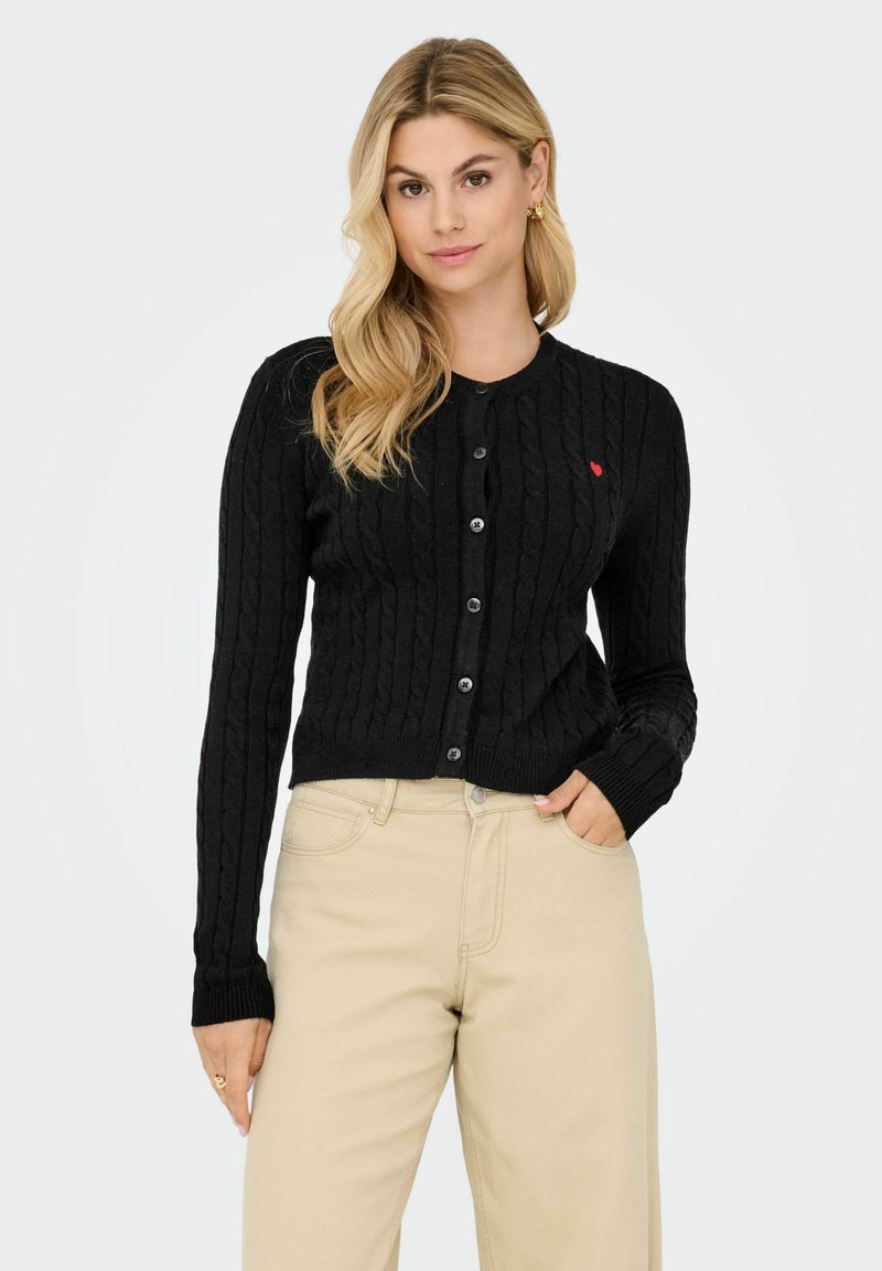 Cardigan nero a maglia di cotone con maniche lunghe, scollo rotondo e chiusura con bottoni. Presenta un piccolo dettaglio a forma di cuore rosso sul lato sinistro del petto.