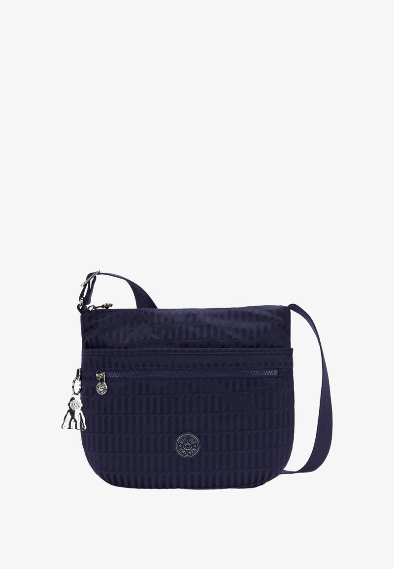 Námořnická nylonová crossbody taška s texturovaným povrchem, jednou zipovou kapsou, nastavitelným popruhem a kovovým detailem ve tvaru charm. Kulaté logo je vyraženo na přední straně.