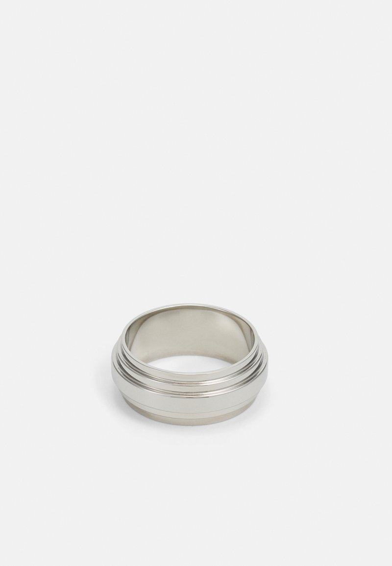 Bague en métal argenté avec une surface lisse, présentant plusieurs bandes empilées et une forme arrondie. Fini réfléchissant, design minimaliste.