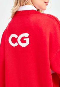 Rode gebreide trui met een wit "CG" logo op de achterkant. Inclusief een gestructureerde afwerking en een geribbelde kraag. Eenvoudig, oversized ontwerp.