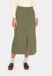 Falda midi verde oliva con una abertura frontal, confeccionada en algodón. Presenta dos bolsillos frontales y una cinturilla simple con cierre de botón.