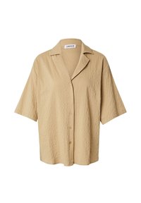 Kurzarmpoloshirt mit Knopfleiste in hellem Beige, aus strukturiertem Stoff mit leicht zerknitterter Oberfläche und mit eingeschnittenem Kragen.
