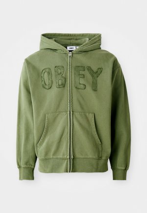 Olivgrüne Zip-Hoodie aus weichem Stoff, mit dem Wort "OBEY" in strukturierter Stickerei auf der Vorderseite, seitlichen Taschen und einer Kapuze.