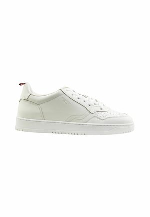 Baskets blanches en cuir avec des détails perforés, lacets blancs plats et une semelle en caoutchouc texturée. Présente un petit accent rouge au niveau du talon.