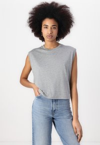 Gray sleeveless cropped t-shirt made of soft fabric with a round neckline, paired with high-waisted light blue jeans.