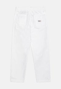 Białe bawełniane spodnie z elastycznym paskiem, posiadające dwie tylne kieszenie oraz prostą nogawkę. Gładka tekstura i prosta konstrukcja.