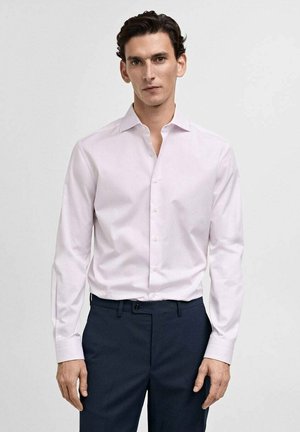 Light pink long-sleeve shirt with a pointed collar, single chest pocket, and button placket, paired with dark trousers. Smooth fabric texture.
