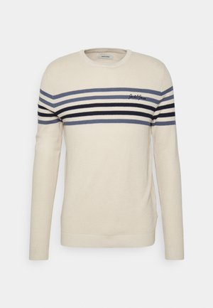Pull léger beige avec des rayures horizontales en marine, gris et noir. Tissu en tricot texturé avec un col ras du cou et des poignets côtelés. Détail du logo.