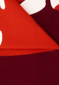 Tkany materiał w intensywnym pomarańczowym i głębokim burgundzie z miękką teksturą. Posiada odważne abstrakcyjne wzory w kontrastujących kolorach.
