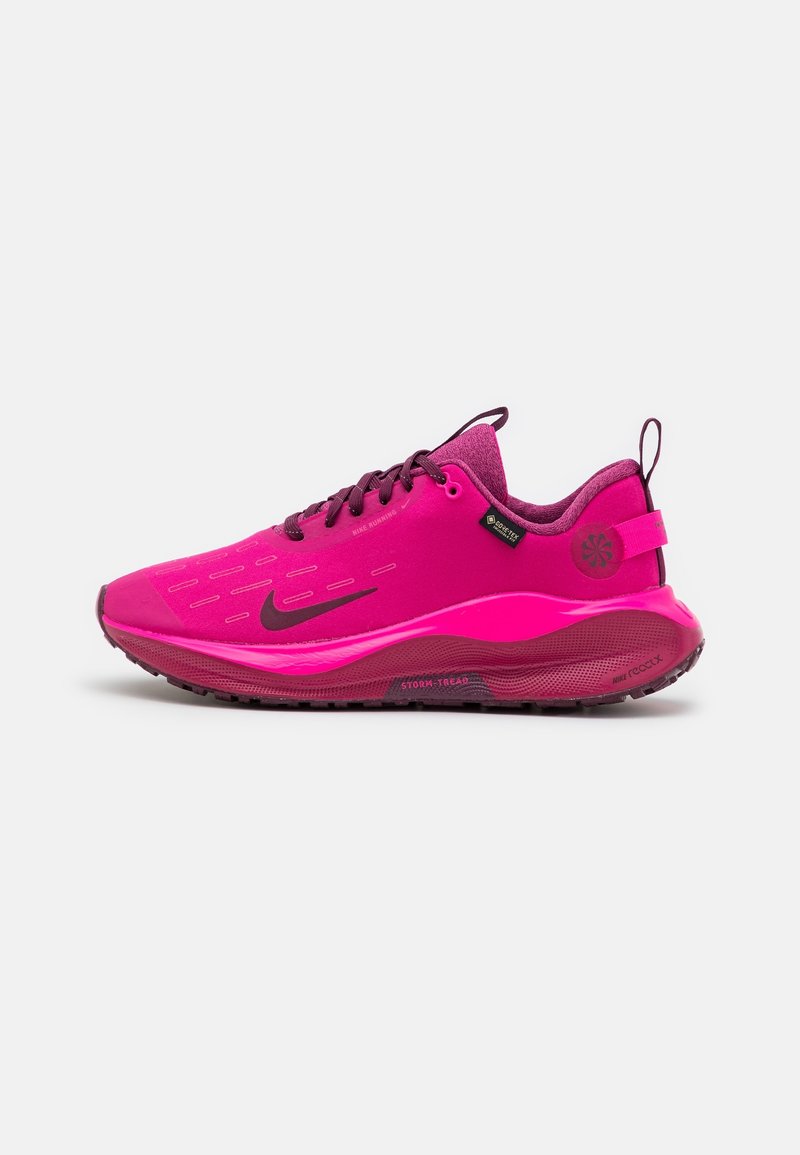 Chaussure de course Nike rose vif avec logo swoosh noir, fermeture à lacets et semelle texturée sur fond blanc.