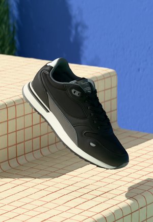 Black athletic shoe with smooth synthetic material, grey accents, and white sole. Designed with a lace-up front and padded collar.