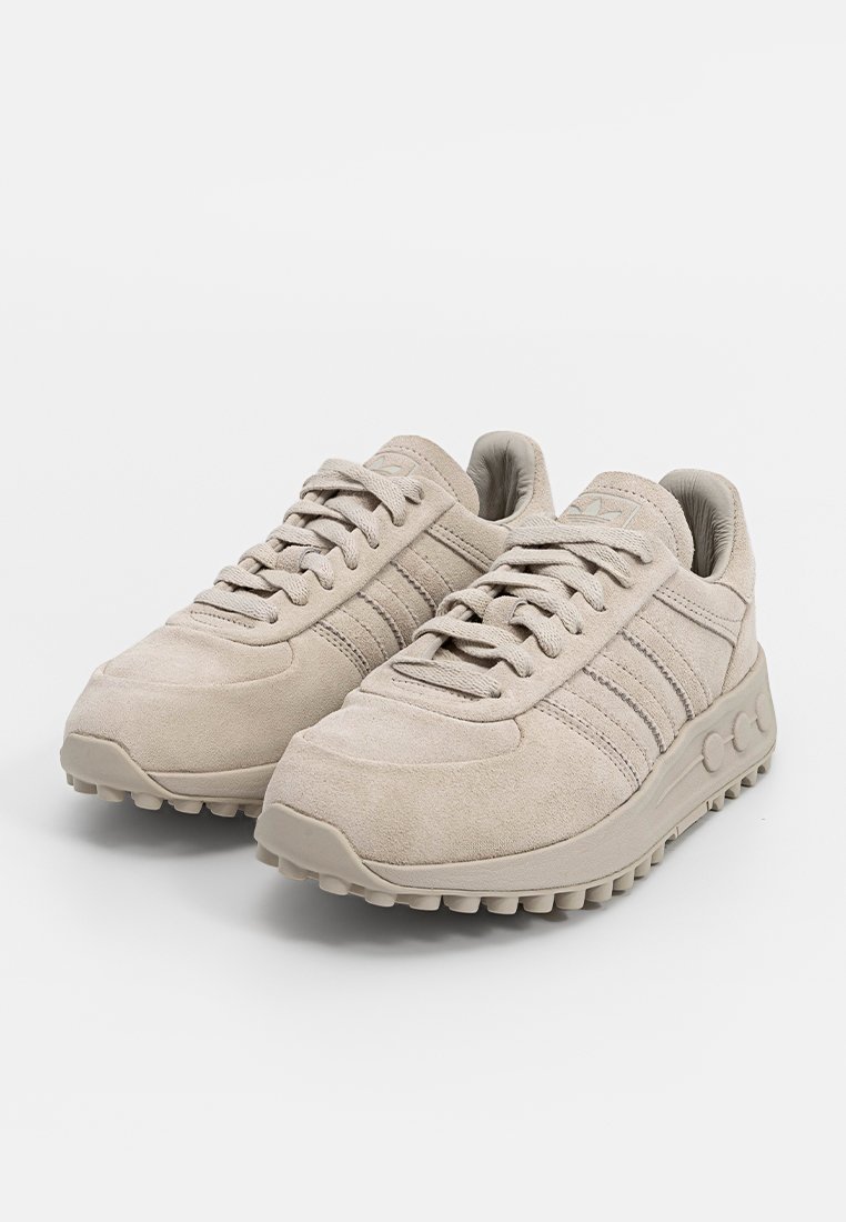 Beige suède sneakers met een textuur oppervlak, voorzien van drie stripes, een gevoerd kraagje en een rubberen zool met een patroon.