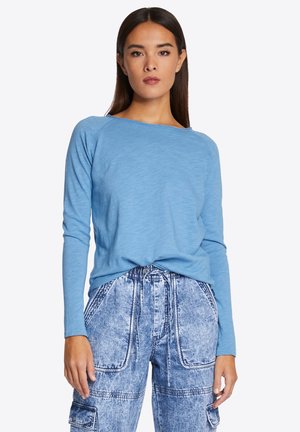 Himmelblaues Langarmoberteil mit Rundhalsauschnitt, weichem Stoff und lockerer Passform, kombiniert mit himmelblauen Denim-Cargohosen mit einer Kordelzug-Taille.